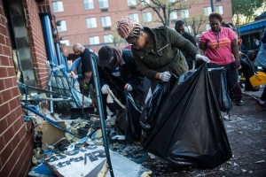 Members of the community clean up debris from a pharmacy that was set on fire during rioting after the funeral of Freddie Gray, on April 28, 2015 in Baltimore, Maryland. (GETTY/ANDREW BURTON)