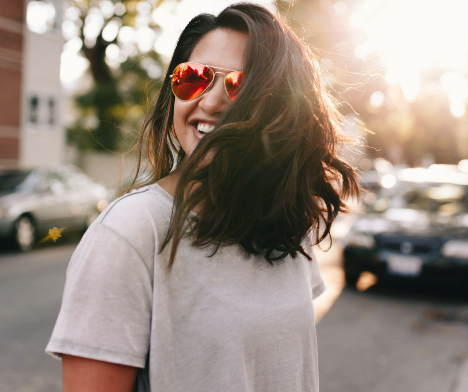 woman outside with sunglasses smiling happy and healthy