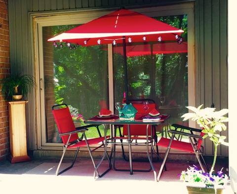 table and chairs with a decorated umbrella on an apartment balcony